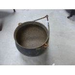 A vintage iron cauldron with carrying handle.