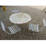 A rustic metal garden table and three chairs.