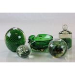 Four green glass paperweights and a similar bowl..