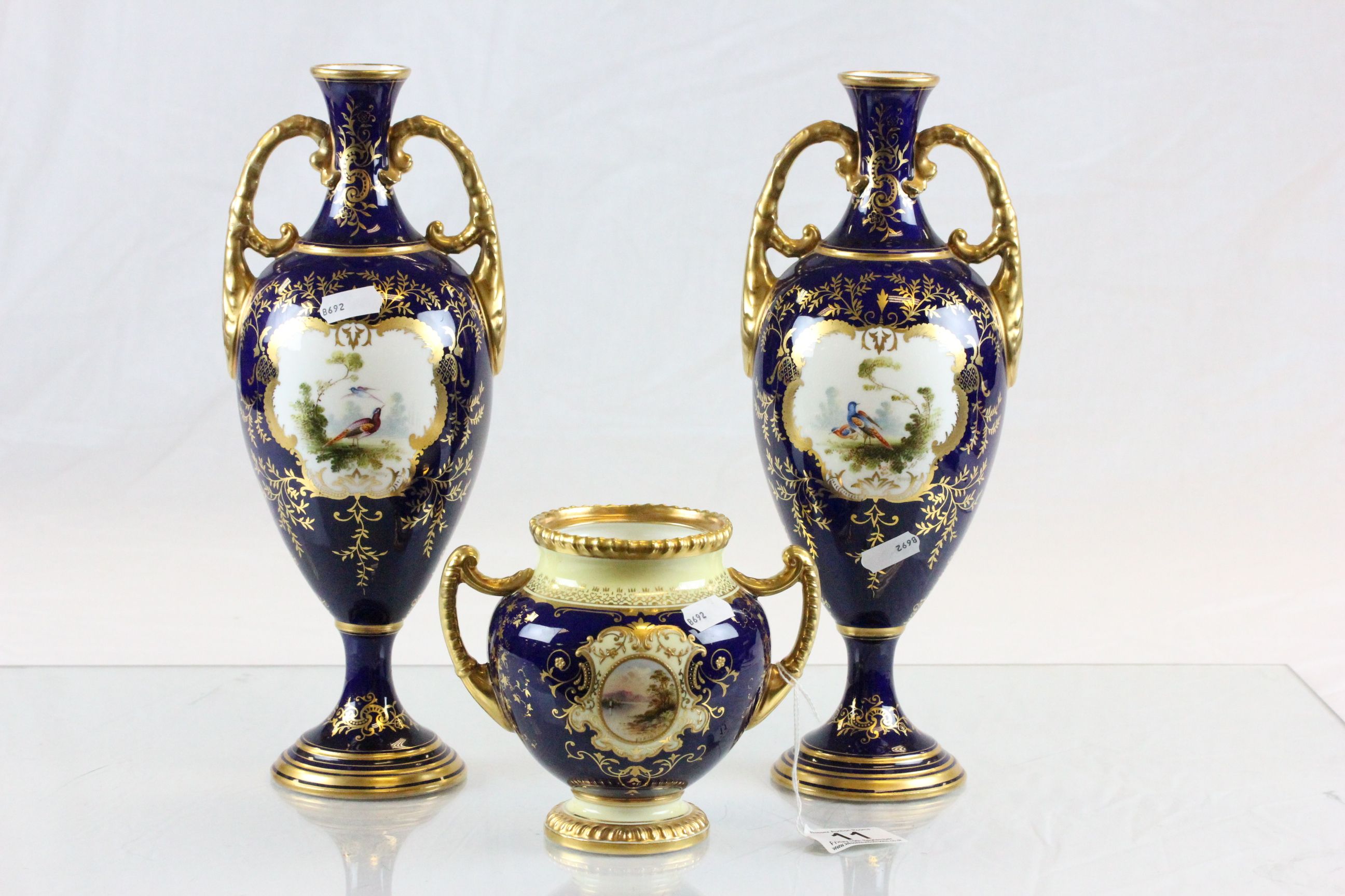 Pair of twin handled Coalport vases with hand painted decoration and a similar squat vase