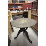 A 19th Century Eastern brass topped table with ornately carved tripod base