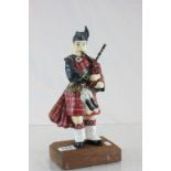 Heavy cast doorstop modelled as a Scots piper on wooden base