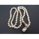 A long string of cultured pearls with silver clasp set with rubies and other semi precious stones