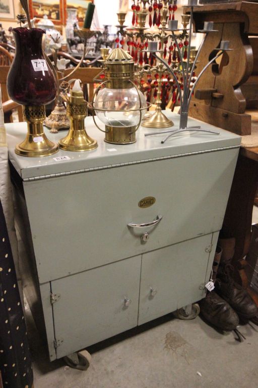 A vintage metal cabinet with lift up top and cupboards beneath