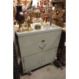 A vintage metal cabinet with lift up top and cupboards beneath