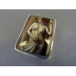 A silver pill box with nude image to the lid