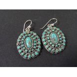A pair of sterling silver oval shaped turquoise set drop earrings