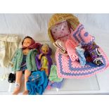 Two vintage plastic dolls, one with string pull voice, a wicker cradle and a bag of vintage dolls