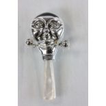 A silver babies rattle with mother of pearl handle