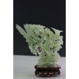 A Jadeite carved sculpture of birds in a tree raised on a wooden base.