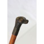 An antique dog training stick with dog head handle with glass eyes.