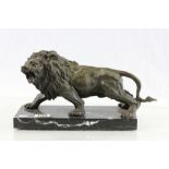 A bronze lion figure raised on a black marble base..