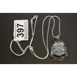 A silver Buddha pendant necklace set with garnets on a silver chain