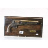 A replica half model of a Colt 45 on wooden plaque.