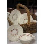Six Wedgewood Soup dishes with saucers in a wicker basket