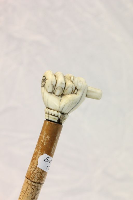 A vintage walking stick with carved ivory clenched fist possibly Masonic.