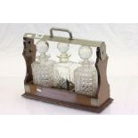 Oak & silver plated three bottle Tantalus with bottles