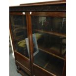 1920's oak show cabinet with twin glazed doors to the front and graduating shelving enclosed on a