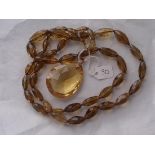 A large heavy carved amber faceted glass necklace with 9ct mount