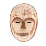 Early 20th century, Gabon, Okuyi male mask. A painted carved wood mask, the face ringed with a