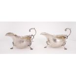 A pair of George V silver sauce boats. A pair of silver helmet-shaped sauce boats, the wavy rim over