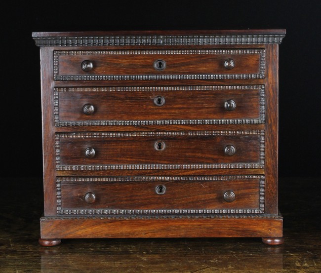 An Early 19th Century Miniature Rosewood Veneered Chest of Four Long Drawers edged in ebonised