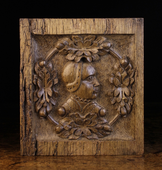 A Small 16th Century Oak Panel carved with a profile of a woman's head in a ring adorned with