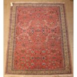 A Late 19th Century Persian Rug woven with floral motifs on a red ground and framed in a cream