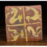 A 15th Century Terracotta Tile decorated in yellow slip with four creatures, 5 ins (13 cms) square.