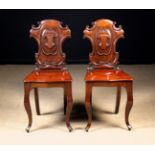 A Pair of 19th Century Mahogany Hall Chairs. The shield shaped backs carved with crests.