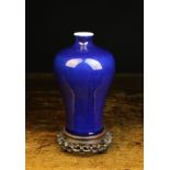 A Cobalt Blue Glazed Meiping Vase standing on a pierced and carved wooden stand 9¼ ins (23.