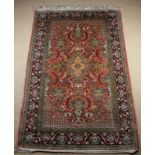 A Persian Carpet woven with a central medallion surrounded by urns of flowers and birds amongst