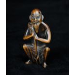 An 18th/19th Century Japanese Carved Wooden Netsuke in the form of a crouching sennin,