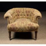 An Edwardian Upholstered Tub Armchair with deep buttoned back and sprung seat standing on turned