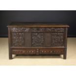 A Carved Oak Mule Chest dated 1622. The planked top with moulded edge above a carved facade.