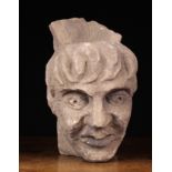 A Medieval Style Carved Stone Head, 9½ in (24 cm) in height.