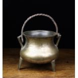 A 17th Century Bronze Cauldron having a wrought iron swing handle looped through triangular lugs