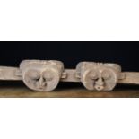An Ethnic Wooden Rail naively carved with two heads side by side, 53½ in (136 cms) in width.