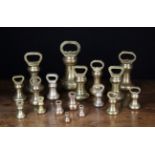 Eighteen Graduated Bell Shaped Brass Kitchen Weights; ranging from 14 lbs to an ounce.
