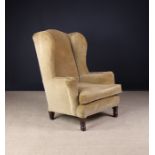 An Upholstered Wing Armchair covered in a tawny gold velvet standing on turned feet,