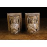 A Pair of Small Carved Oak Corbels in the form of angels with folded wings bearing heraldic shields
