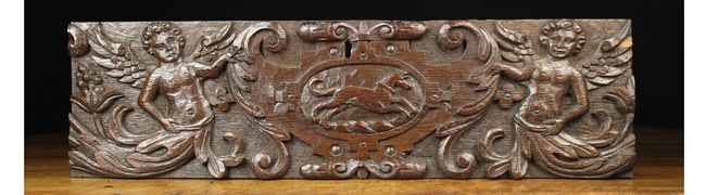A Relief Carved Oak Panel centred by a leaping dog in a cartouche flanked by winged caryatids,