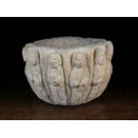 A Stone Font: The fluted sides carved in relief with the twelve disciples, 7½ in (19 cm) high,