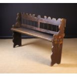 An 18th Century Provincial Elm Bench having a wavy cut back rail above a row of stick spindles,