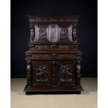 A 17th Century Flemish Two Part Cupboard having moulded panel sides and a relief carved facade.