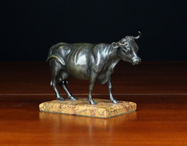 A Small Bronze Figure of a Cow mounted on a brêche marble socle, 4¾ in (12 cm) high, 6½ in (16.