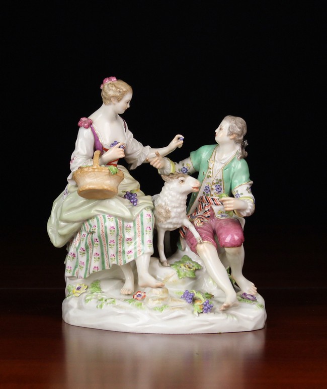 A Meissen Porcelain Figure Group: A Lady & Gentleman dressed in 18th century style attire sat