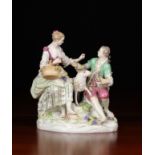A Meissen Porcelain Figure Group: A Lady & Gentleman dressed in 18th century style attire sat