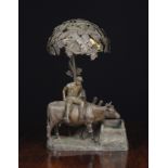 A Bronze Patinated Spelter Occasional Lamp modelled with a man sat upon a cow at water trough,