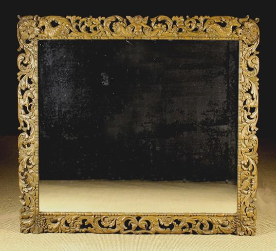 A Large Rectangular Wall Mirror in a 17th century pierced oak frame richly carved with winged